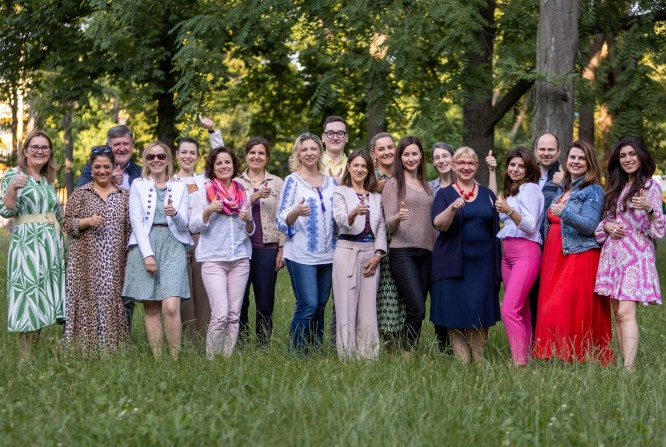 Eine Gruppe von Männern und Frauen lächelt und posiert für ein Foto im Gras, das Stepic Charity CEE liebenswerte Team.