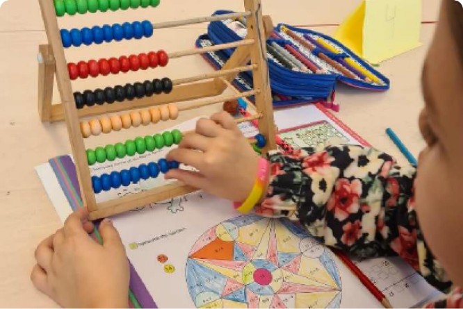 A child supported by charity skillfully counts using an abacus, enhancing their mathematical abilities.